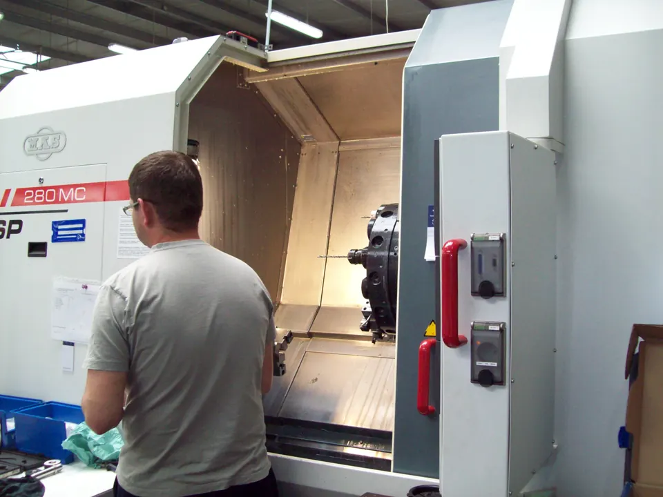 Operator at the open work area of a CNC lathe