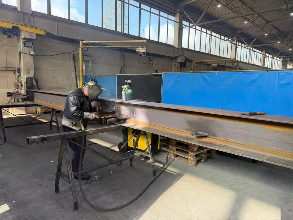 Welder working on a long steel beam