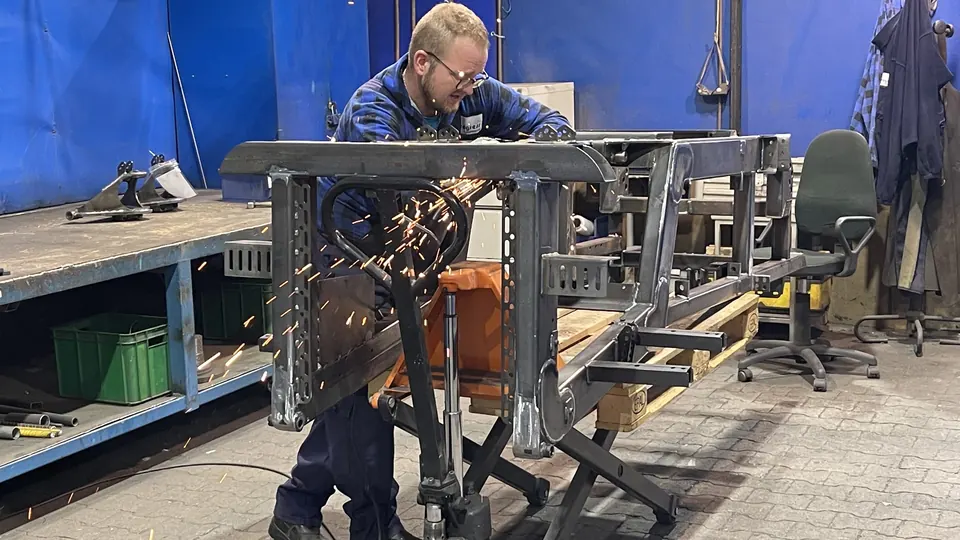 Grinding welds on a steel frame at a manual station
